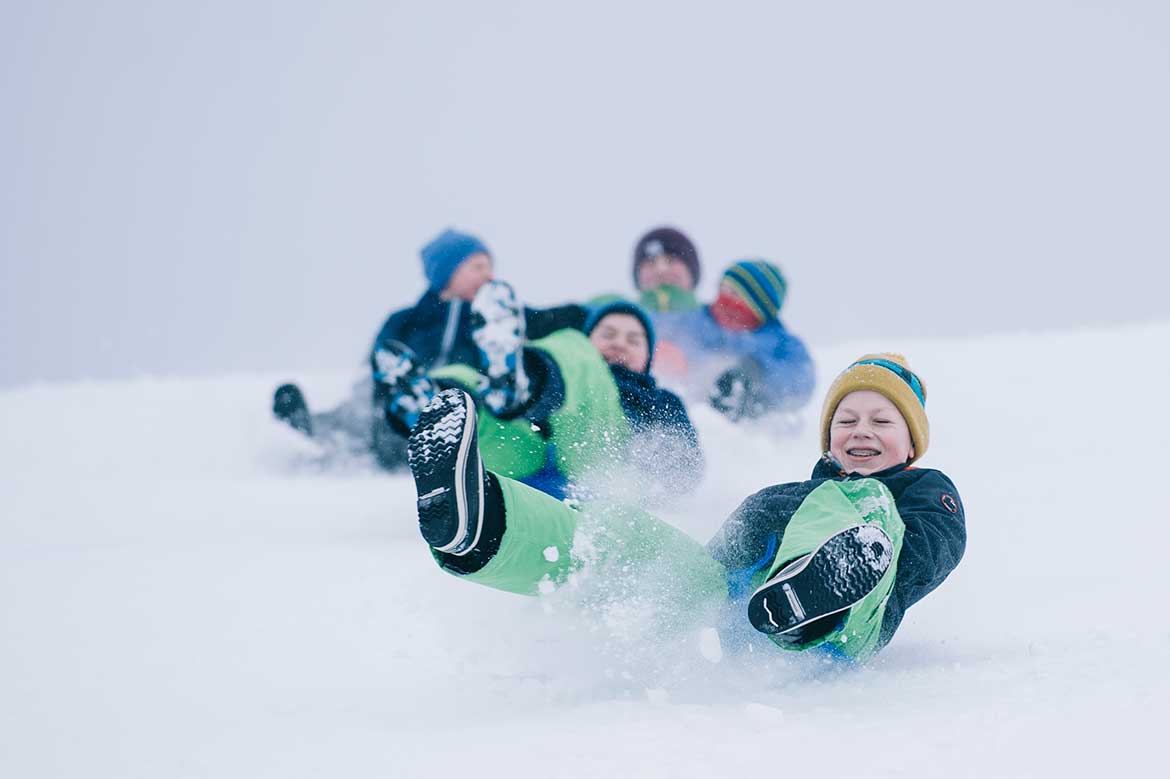 Två killar som åker stjärtlapp nerför en backe