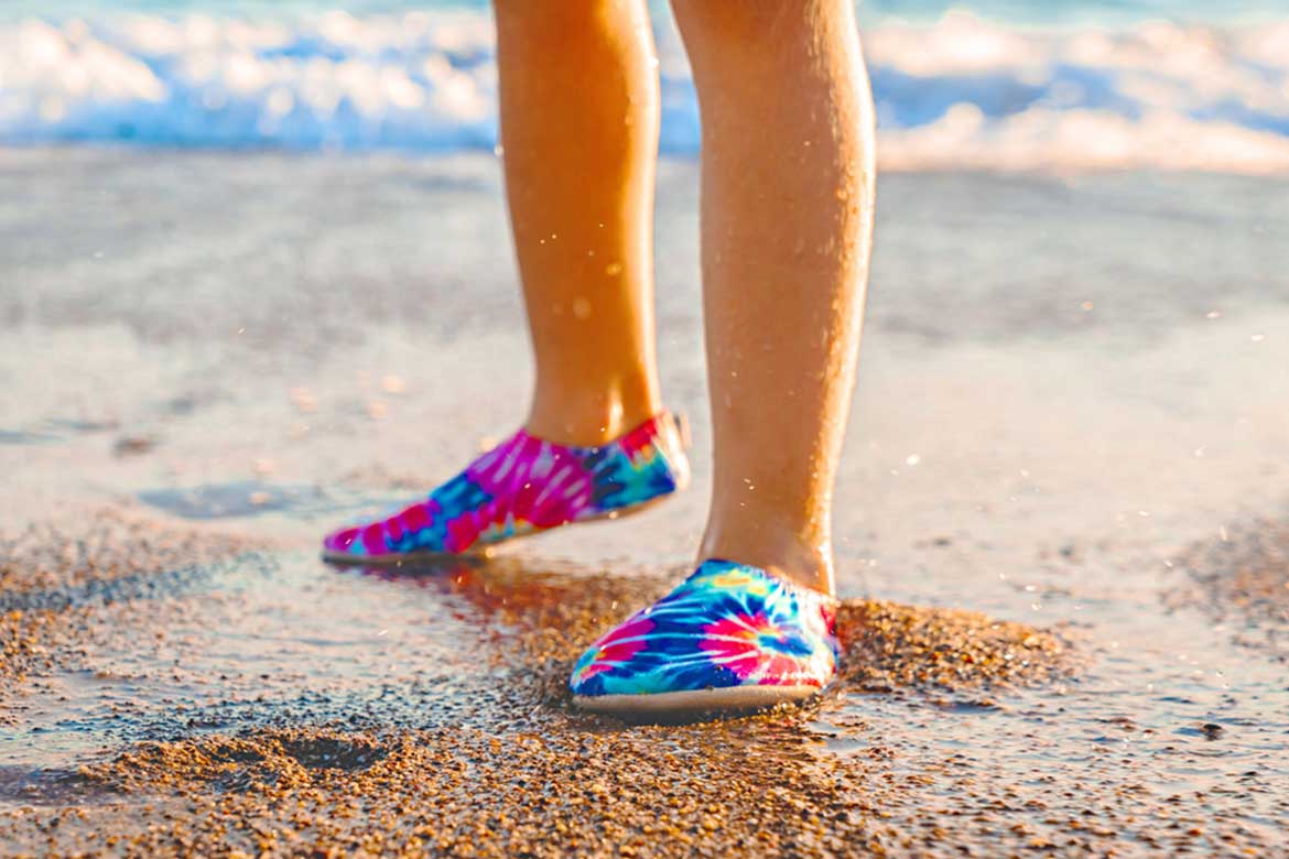 Färgglada Slipstop badskor skyddar små fötter mot het sand och hala underlag – perfekt för lek på stranden.